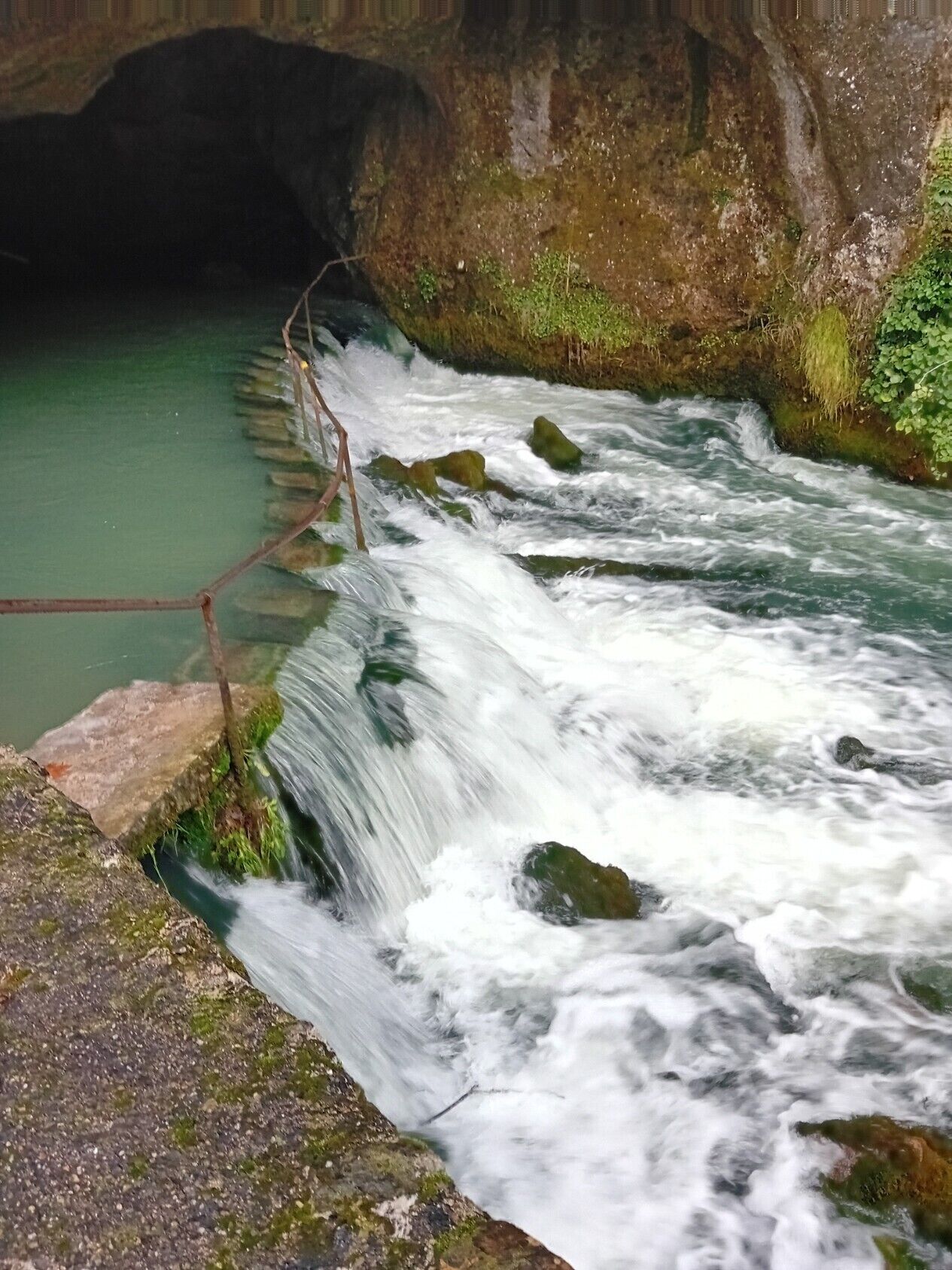 A river flowing over rocks with a bridge.