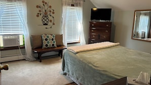 A bedroom with a bed, a dresser, a TV, and a window with blinds. - Remodeled home near the beach (Dunkirk)