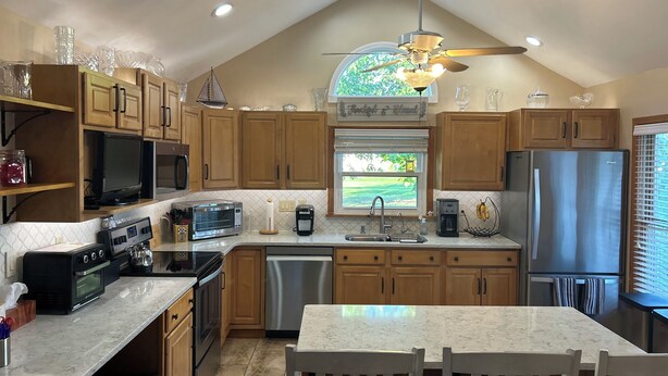 A modern kitchen with wooden cabinets, a stainless steel refrigerator, a microwave, and a dishwasher. - Remodeled home near the beach (Dunkirk)