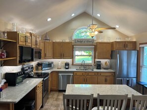 A modern kitchen with wooden cabinets, a stainless steel refrigerator, a microwave, and a dishwasher. - Remodeled home near the beach (Dunkirk)