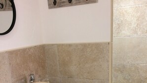 Un baño con tocador de madera, lavamanos color beige, perchero y zona de ducha.