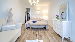 Ein Schlafzimmer mit einem Bett, einem Schminktisch, einem Nachttisch, einer Lampe, einer Deckenleuchte und einem Spiegel.