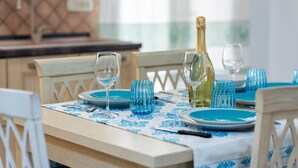 A dining table set with blue plates, glasses, and a bottle of champagne. - Villa 'Ivonne's' with Private Terrace, Wi-Fi and Air Conditioning (Villasimius)