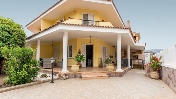 A two-story house with a balcony, potted plants, and a tiled patio. - Villa 'Ivonne's' with Private Terrace, Wi-Fi and Air Conditioning (Villasimius)