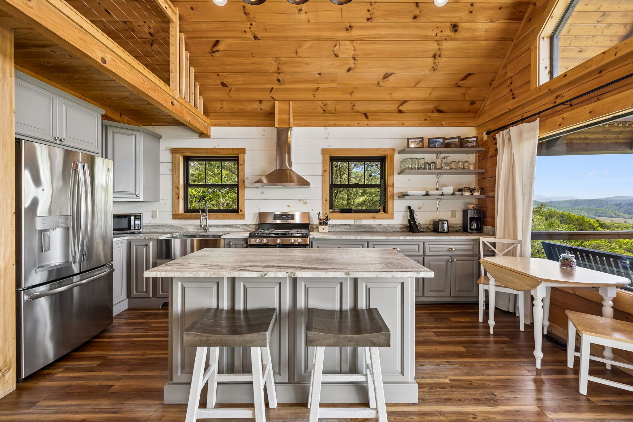 A modern kitchen with wooden beams, stainless steel appliances, and a large island with bar stools.