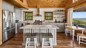 Eine moderne Küche mit Holzbalken, Edelstahlgeräten und einer großen Kochinsel mit Barhocker.