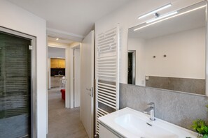 Een moderne badkamer met een witte wastafel, een grote spiegel en een handdoekrek.