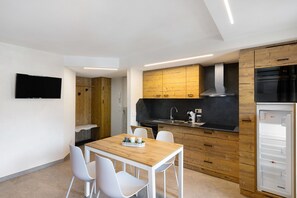 Een moderne keuken met houten kastjes, een inbouwoven en een koelkast.