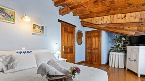 Un dormitorio con una cama, techo de madera, televisión y pared de piedra.