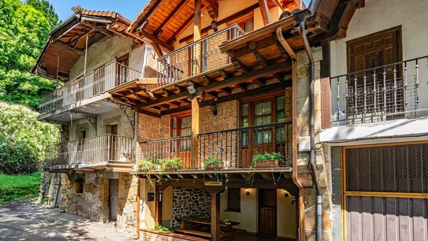 Un edificio de varios pisos con balcones, paredes de piedra y vigas de madera.