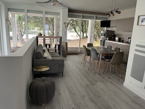 A modern interior with a sofa, dining table, chairs, and a kitchen area.