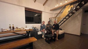 Un salon moderne avec un escalier, une table à manger où l’on peut voir des restes de nourriture, et une grande fenêtre.
