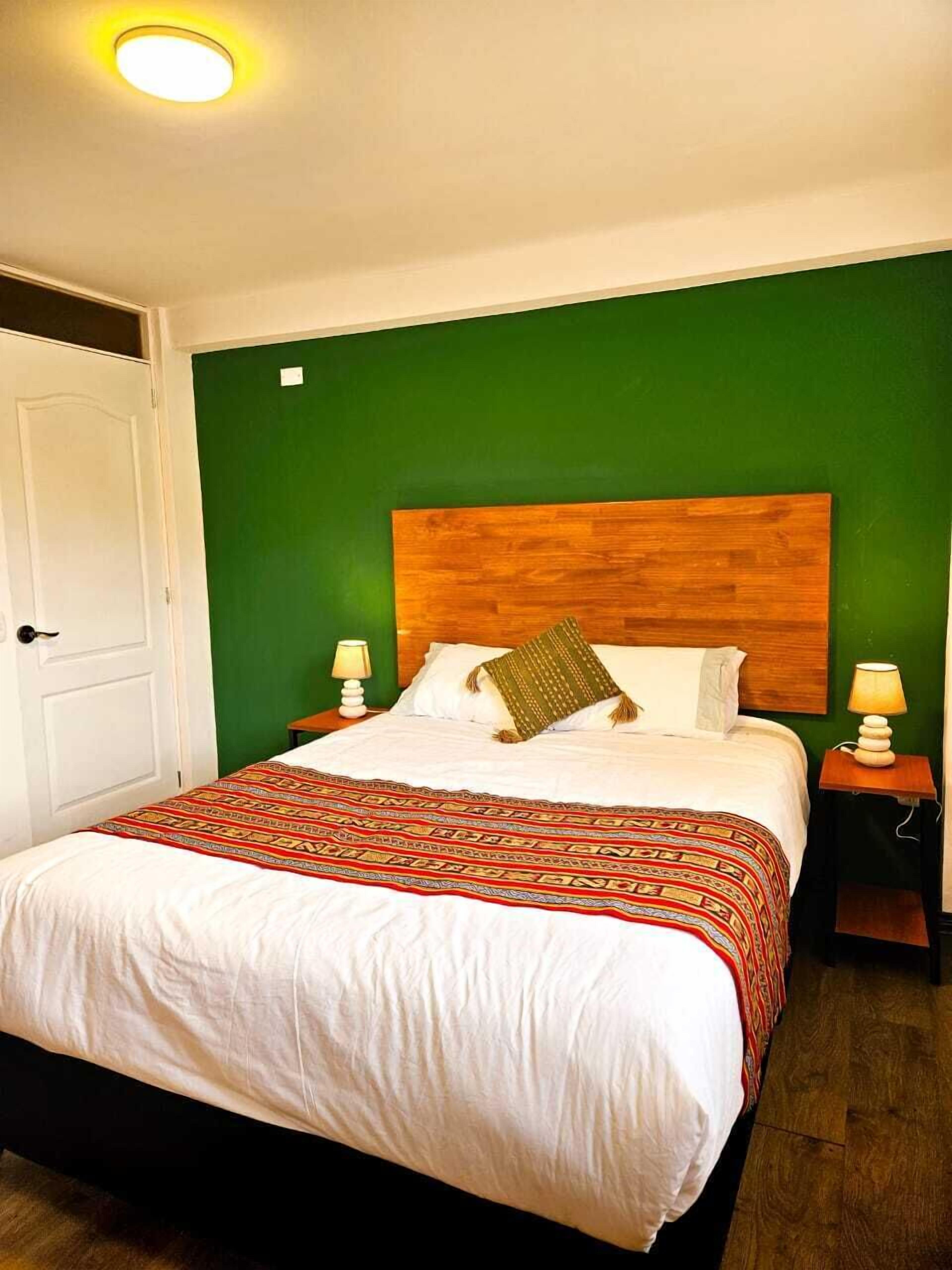 A neatly made bed with a patterned bedspread, a wooden headboard, and two bedside lamps.