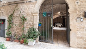Un bâtiment en pierre doté d’une entrée en arc de cercle, de plantes en pot et d’une enseigne portant le chiffre « 10 ».