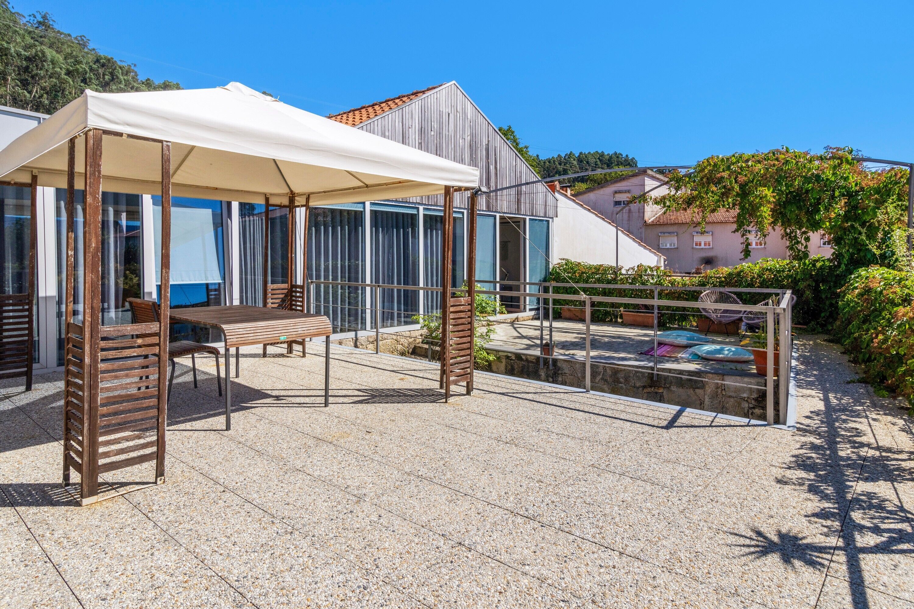Un patio al aire libre con mesa y sillas, una zona de estar techada y una piscina.