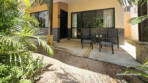 Un edificio moderno con patio coperto, area salotto all'aperto e un piccolo tavolo.