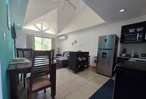 Una cocina moderna con refrigerador, microondas y comedor con sillas y mesa.