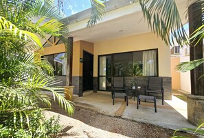 Un edificio moderno con un patio cubierto, mobiliario exterior y una pequeña mesa.