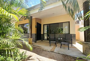 Un edificio moderno con un patio cubierto, mobiliario exterior y una pequeña mesa.