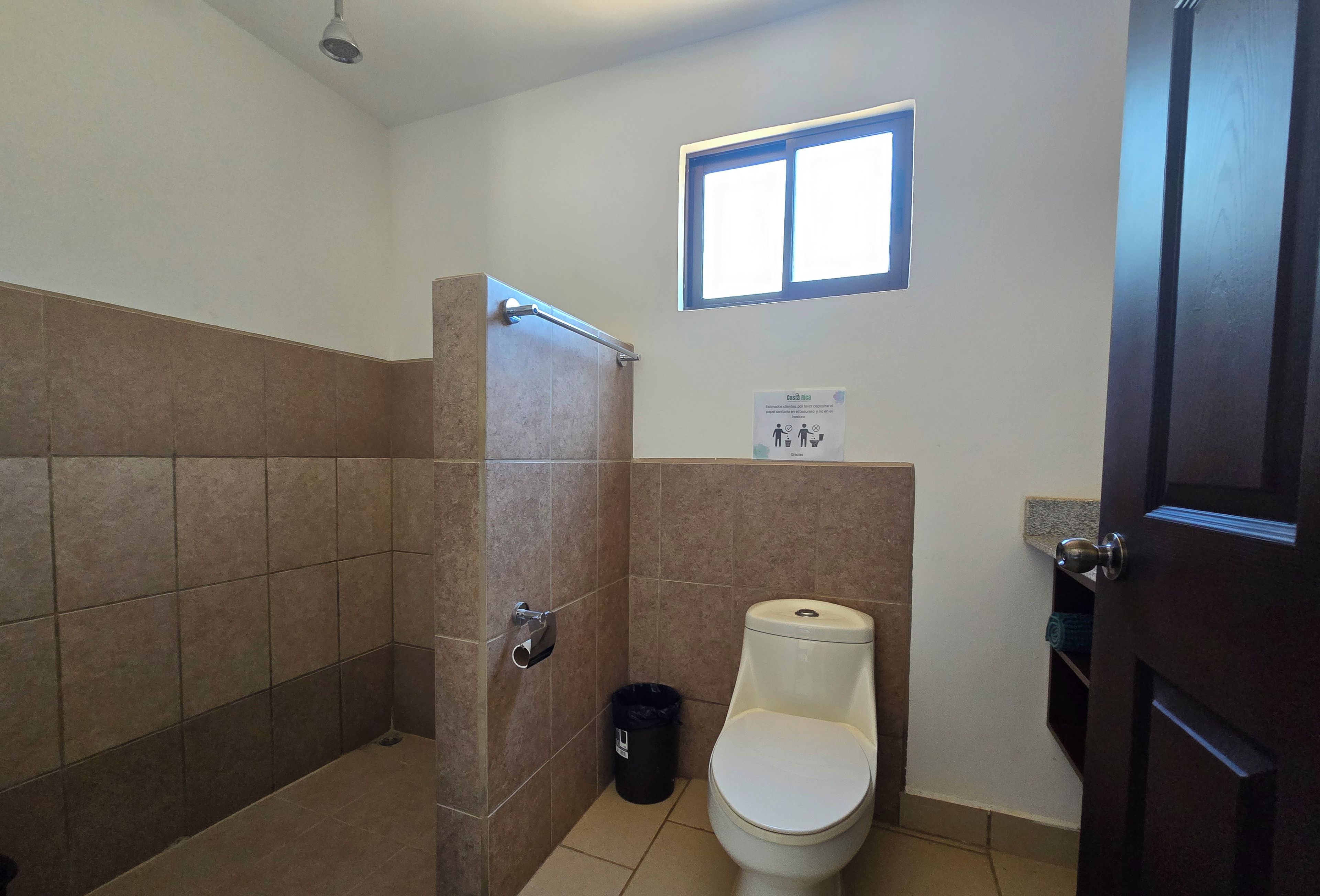 Une salle de bain avec une douche, des toilettes et une fenêtre.