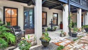 A courtyard with a fountain, potted plants, and a wooden bench. - Cozy Garden Apartment | Heated Pool Access (Savannah)