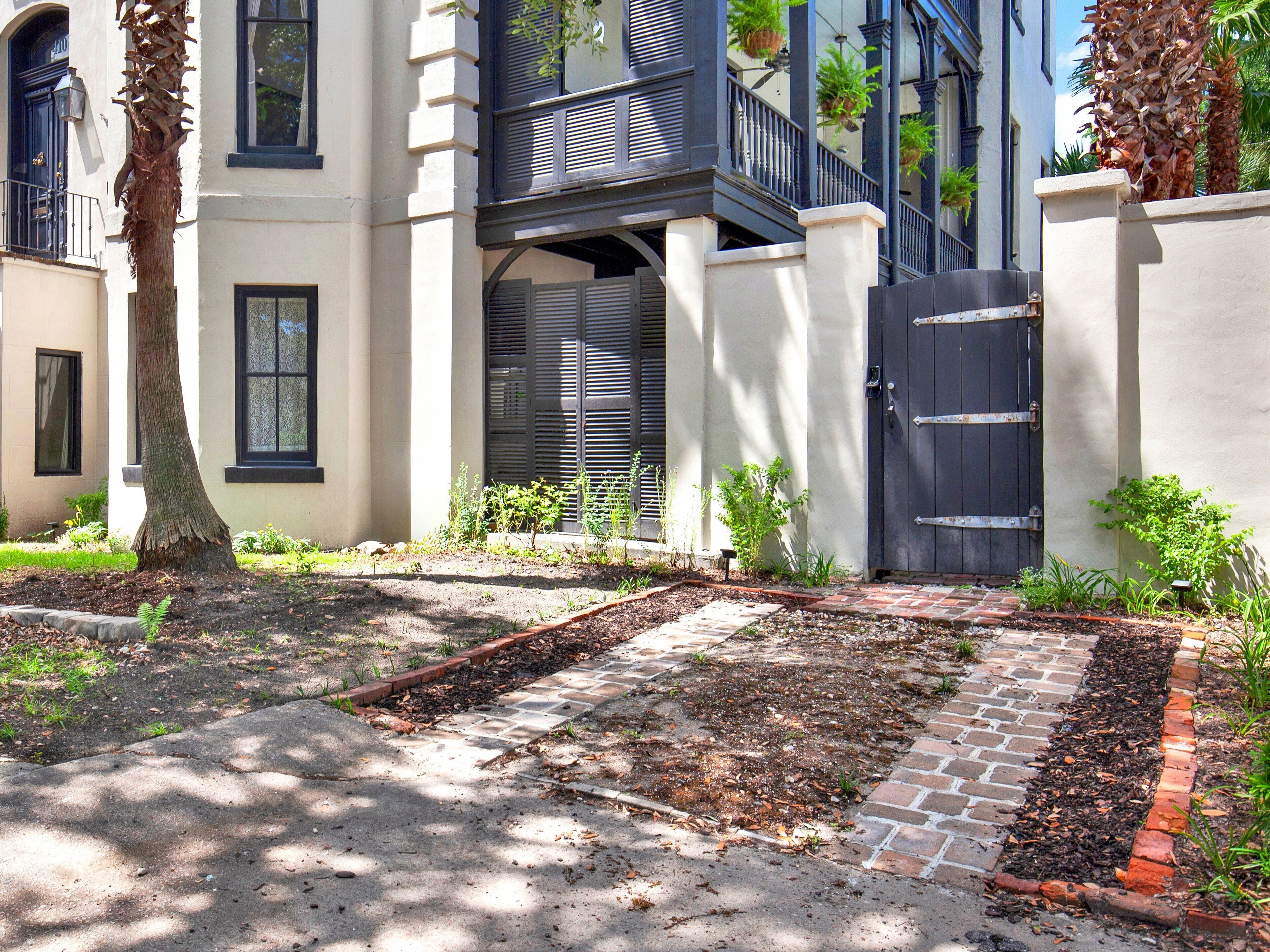 A residential building with a paved driveway, a brick pathway, and a gated entrance.