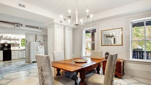 A dining area with a wooden table and chairs, a chandelier, and a view of the outdoors through a window. - Cozy Garden Apartment | Heated Pool Access (Savannah)