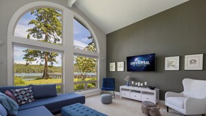 Una sala de estar moderna con un ventanal grande, un televisor de pantalla plana y un mueble blanco para entretenimiento.