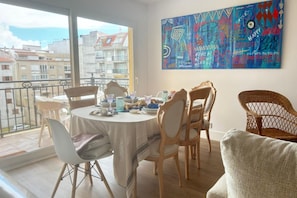 A dining area with a round table, chairs, and a balcony with a view of buildings. - Desconectaengalicia Rosalía II, 100m Silgar Beach (Sanxenxo)