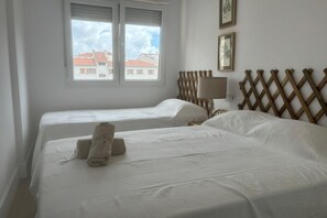 A hotel room with two beds, a window with a view of buildings, a wooden headboard, and a lamp.