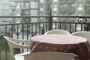 A balcony with a table and chairs, overlooking a residential building with balconies. - Desconectaengalicia Rosalía II, 100m Silgar Beach (Sanxenxo)