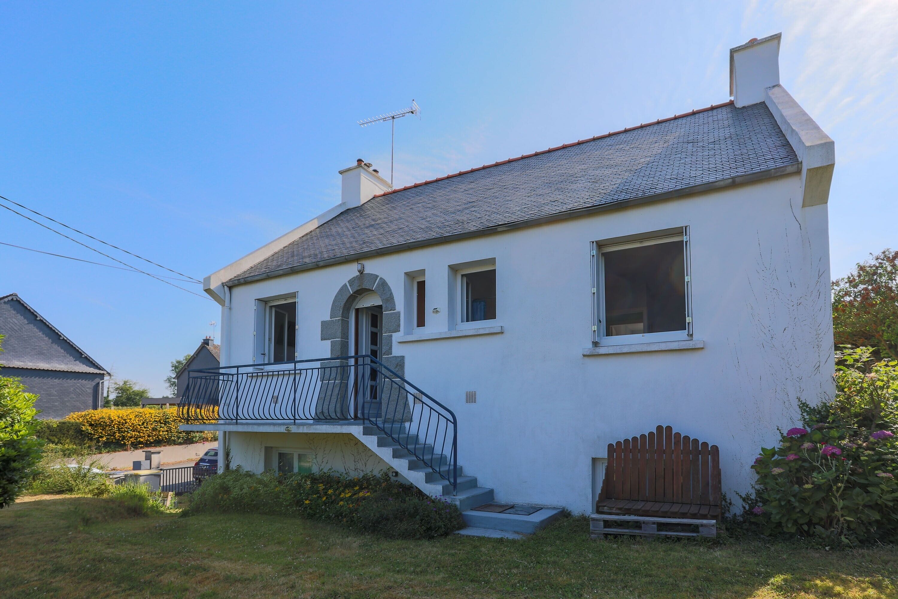 Et toetagers hus med balkon, trappe og træhegn.