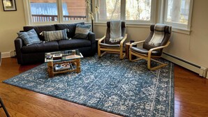 A living room with a dark gray sofa, two armchairs, a glass coffee table, and a blue patterned rug. - Cornet Creek Retreat - Easy Ski, River & Town Access - Semi-Private Garage (Telluride)