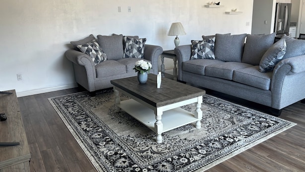 A living room with two grey sofas, a coffee table, and a patterned rug. - BEAUTIFUL 2 STORY HOUSE IN MORENO VALLEY (Moreno Valley)
