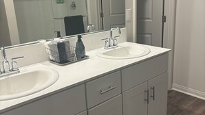 A bathroom with two sinks, a mirror, and a shower. - BEAUTIFUL 2 STORY HOUSE IN MORENO VALLEY (Moreno Valley)
