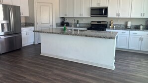 A modern kitchen with white cabinets, a granite countertop, stainless steel appliances, and a wooden floor. - BEAUTIFUL 2 STORY HOUSE IN MORENO VALLEY (Moreno Valley)