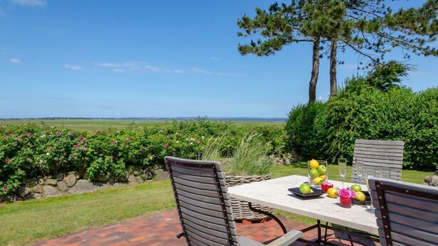 An outdoor dining area with a table and chairs, surrounded by greenery and a view of the countryside. - Heefwai 2-W3 - Holiday apartment "Heefwai 2 W3" in Morsum (Morsum)