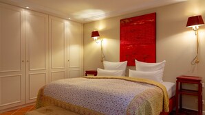 A bedroom with a large bed, two bedside tables, a bench, and a red accent wall. - Heefwai 2-W3 - Holiday apartment "Heefwai 2 W3" in Morsum (Morsum)