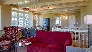 A spacious living room with a red sofa, a patterned armchair, and a dining area with a table and chairs. - Heefwai 2-W3 - Holiday apartment "Heefwai 2 W3" in Morsum (Morsum)