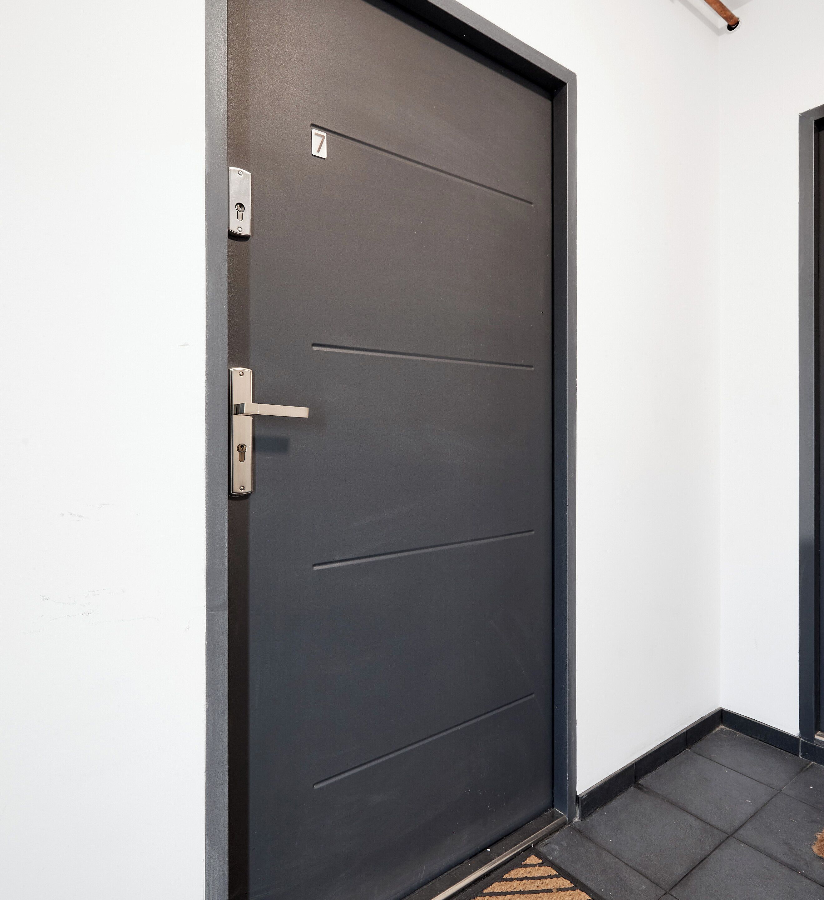 A dark-colored door with a numeric keypad lock, a door handle, and a small window.