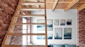 A loft-style room with exposed wooden beams, a brick wall, and a blue sofa. - Starołęcka Apartment with Mezzanine (Poznań)
