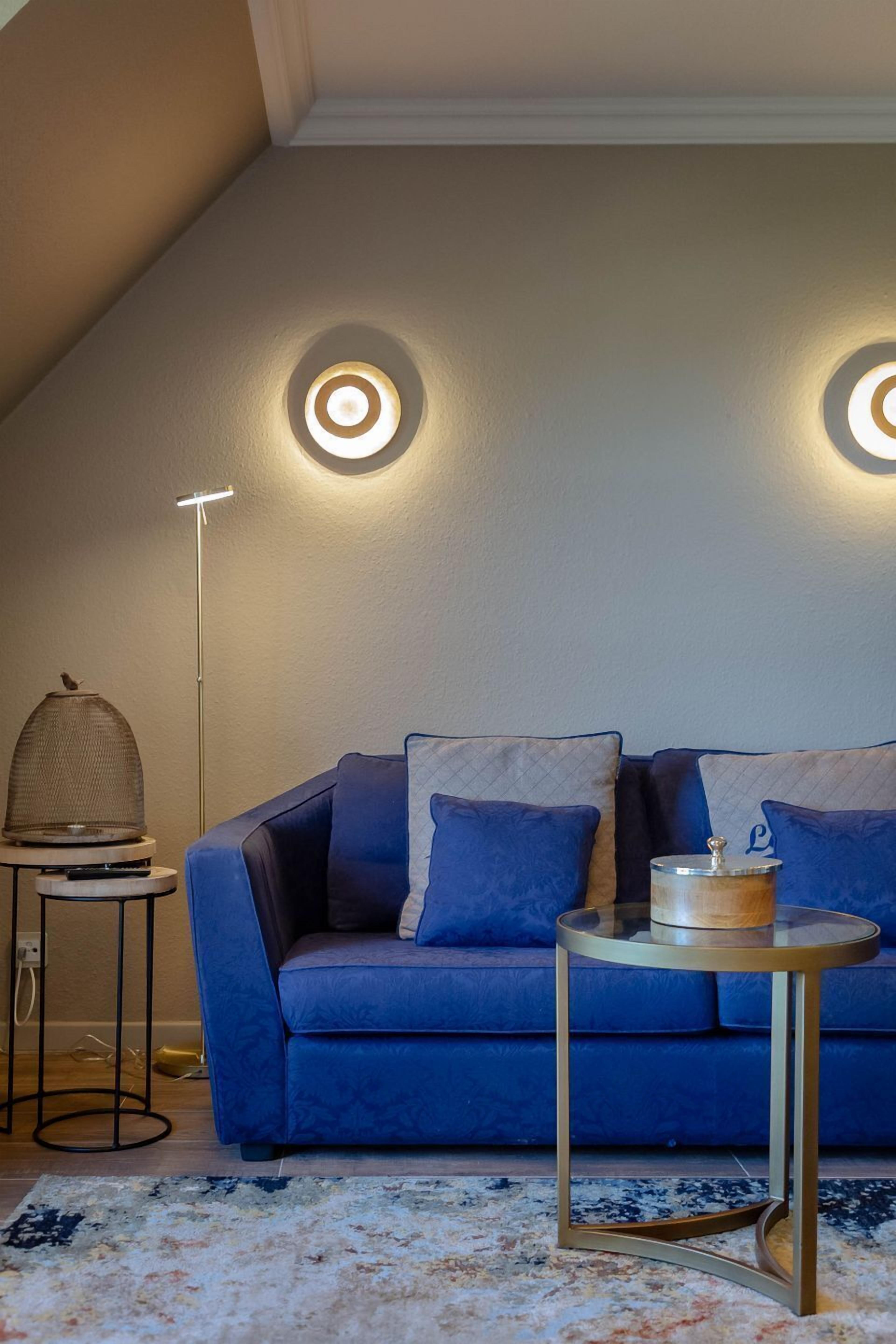 A modern living room with a blue sofa, a round coffee table, and a floor lamp.