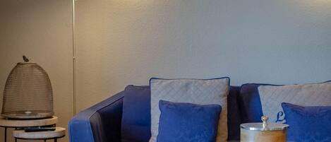 A modern living room with a blue sofa, a round coffee table, and a floor lamp.