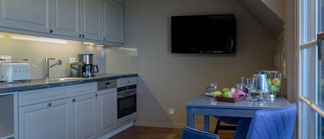 A kitchen with white cabinets, a coffee maker, a toaster, and a table with fruit and glasses.