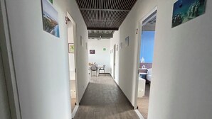 A hallway with a wooden floor, white walls, and framed pictures. There are doors on both sides leading to other rooms. - Torre Yaxche 39 (Cancun)