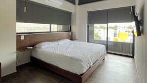 A bedroom with a wooden bed, a nightstand, a window with blinds, and a ceiling fan. - Torre Yaxche 39 (Cancun)
