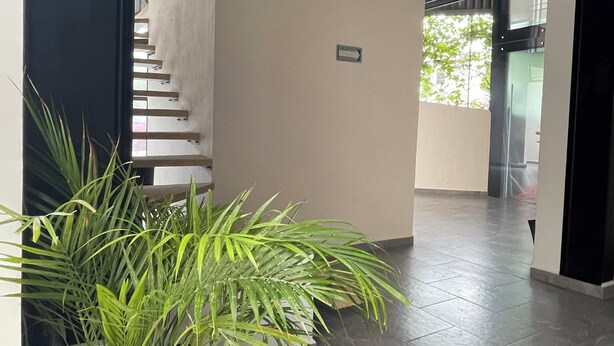 A modern interior with a staircase, a potted plant, and a sign indicating a direction. - Torre Yaxche 39 (Cancun)