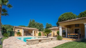 A house with a swimming pool, stone patio, and a covered outdoor seating area.