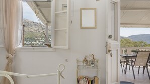 Une porte ouverte donnant sur un balcon d’où l’on peut admirer un paysage montagneux.