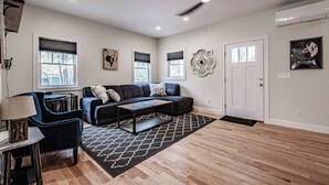 Ein modernes Wohnzimmer mit einer schwarzen Ledersofa, einem Couchtisch und einem gemusterten Teppich.